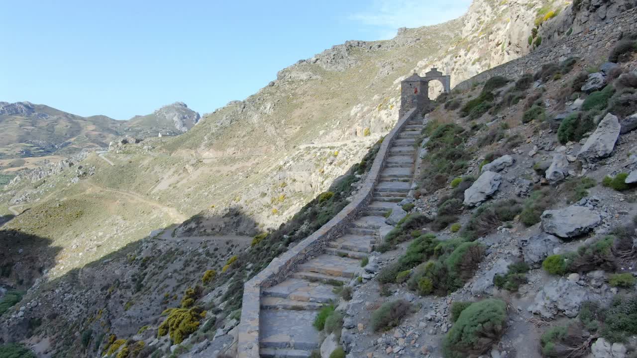 Aerial drone up mountainside stone wall and steps on cliff of mountain