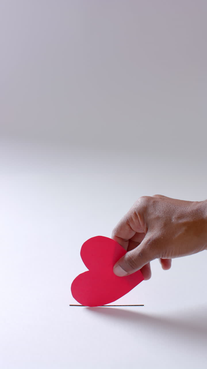 Vertical video of hand of african american man throwing blood drop into hole, slow motion