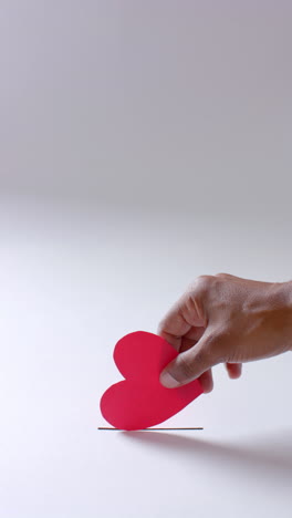 vertical video of hand of african american man throwing blood drop into hole, slow motion