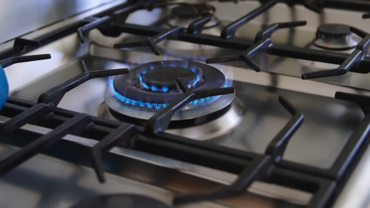 Man placing pan on gas stove hob 4k