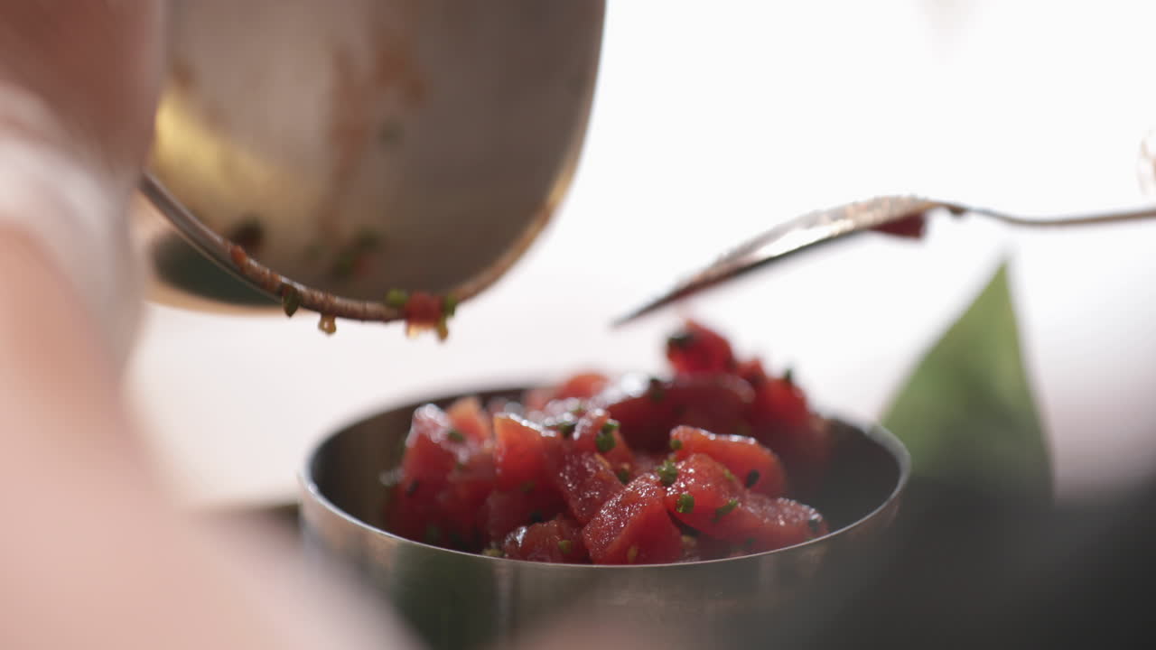 Transferring The Tuna Ceviche With Spring Onions On A Smaller Stainless Bowl. - close up shot