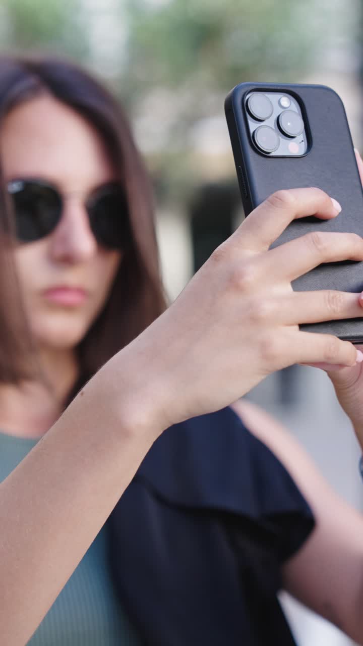 vista vertical de una turista femenina tomando fotos con la cámara de su teléfono inteligente, mallorca