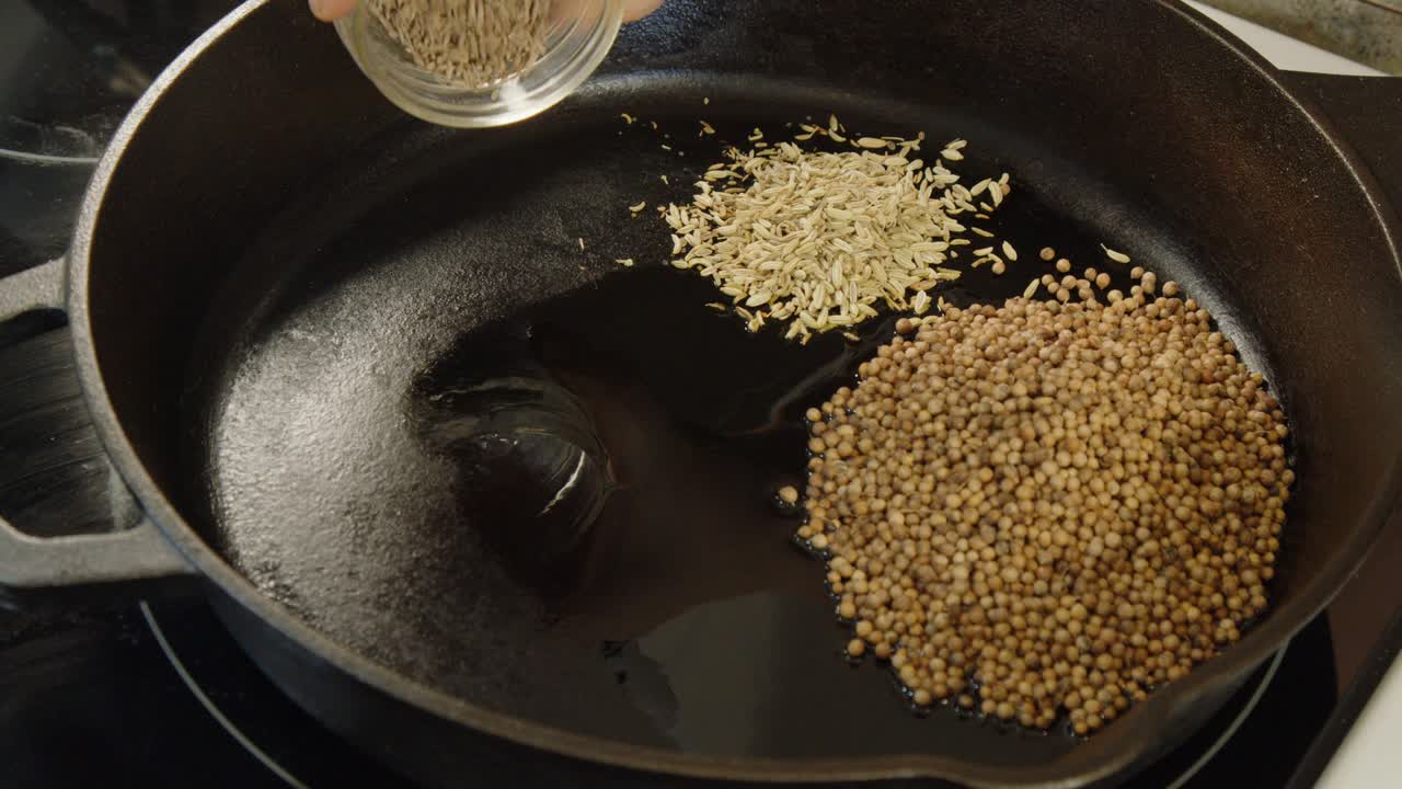 Whole spices added to cast iron pan: coriander, fennel, cumin, pepper