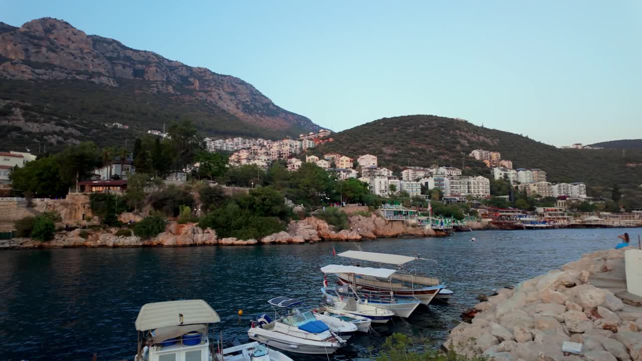 Sweeping left pan across Kaş marina, capturing a beautiful view of boats, water, and the coastal landscape in Turkey.