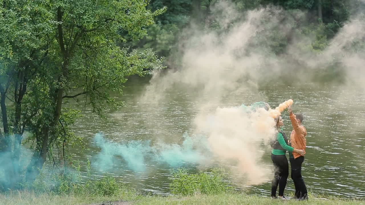 Couple In Love With Smoke Bomb. Young couple with smoke bomb in hands standing in nature