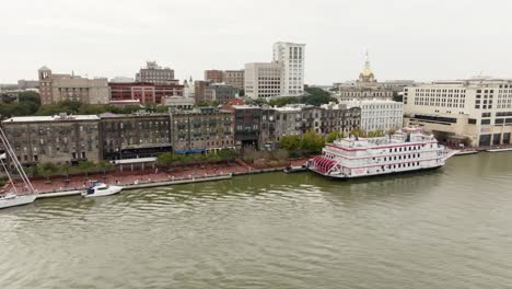 Drone-of-Savannah-Georgia-riverfront-area-along-the-river-with-boats-on-an-overcast-day