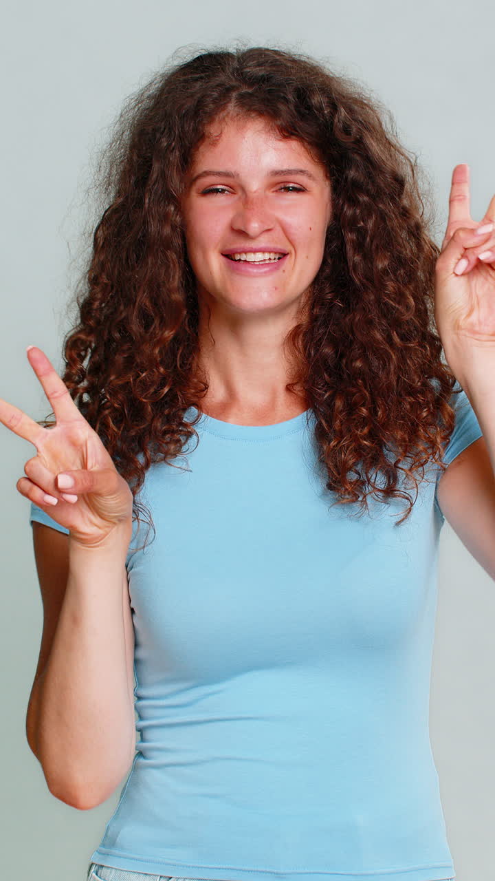 Young happy woman showing peace victory v hand sign cheerful positive joyful optimistic expression
