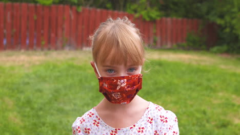 outdoor portrait of a little girl wearing a face mask to help prevent the spread of coronavirus