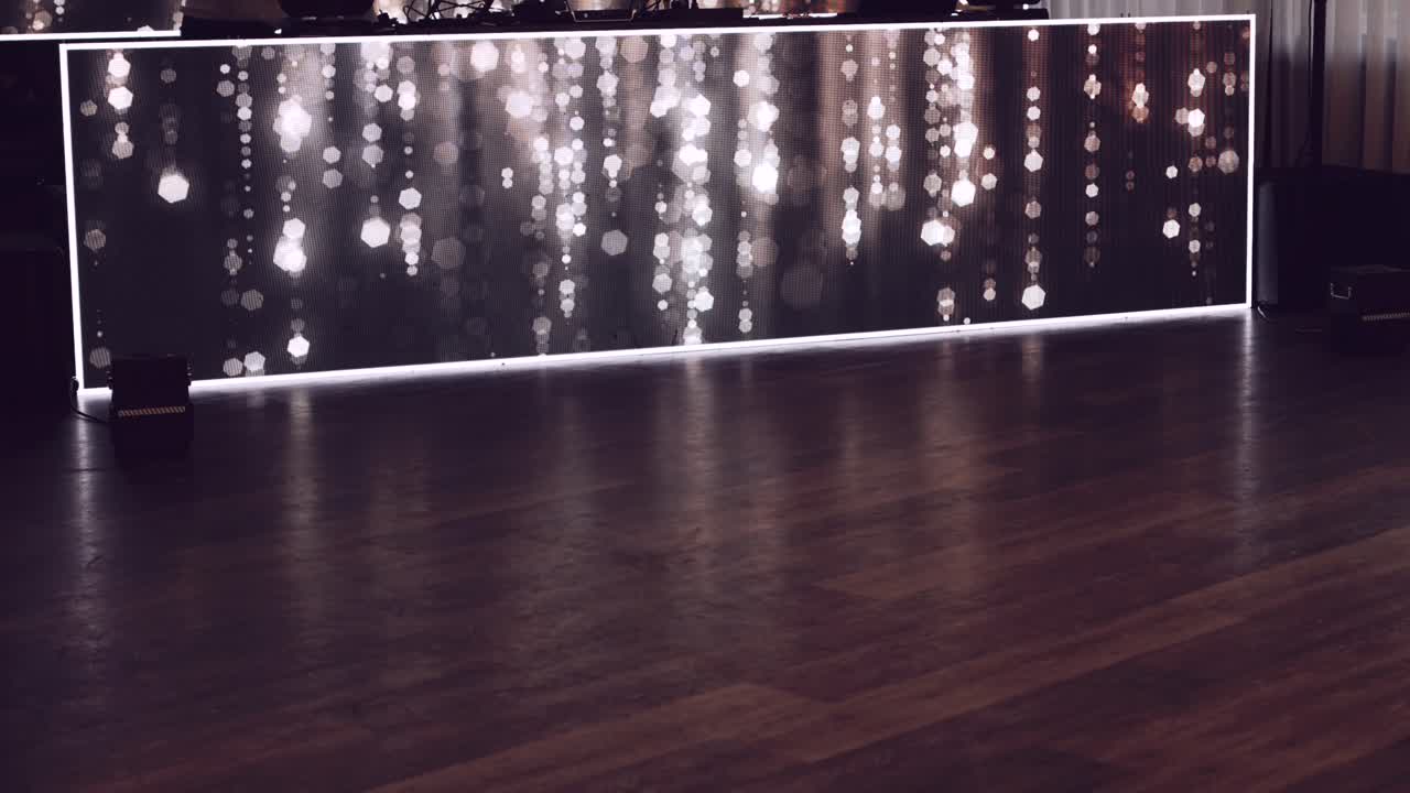Polished wooden floor reflecting warm bokeh lights from a modern decorative panel