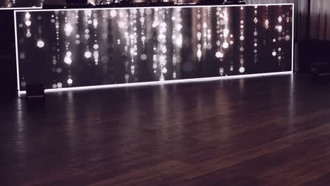 polished wooden floor reflecting warm bokeh lights from a modern decorative panel