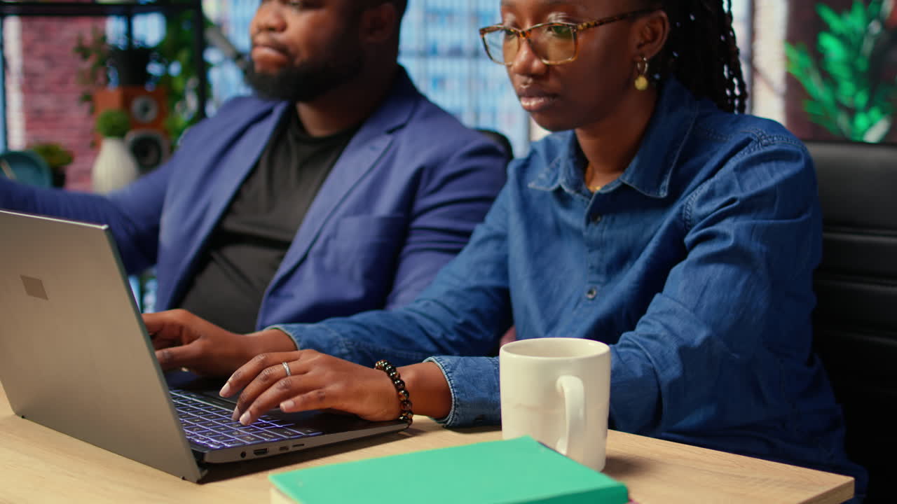 Young couple at desk reading research papers and multitasking