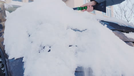 una mujer quita la nieve de su coche