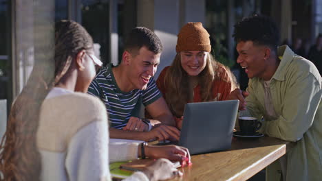 group of students working on a laptop in a cafe
