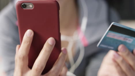 close up of unrecognizable mixed race woman shopping online with credit card and smart phone at home