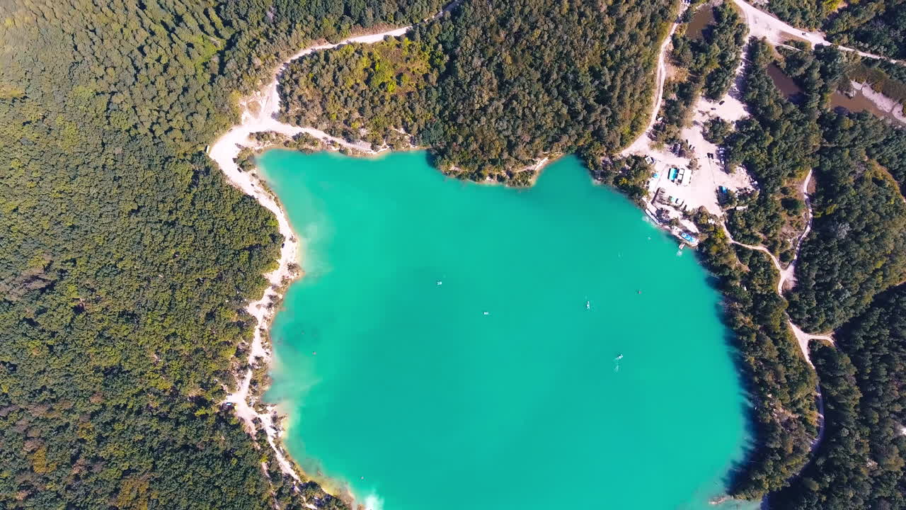 Aerial view of a turquoise lake surrounded by forest