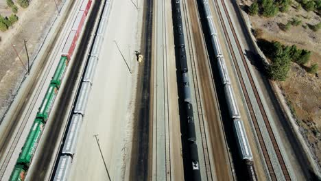 bird's-eye view dolly forward drone shot flying over railroad station in a desert environment on a sunny day next to a highway and a river