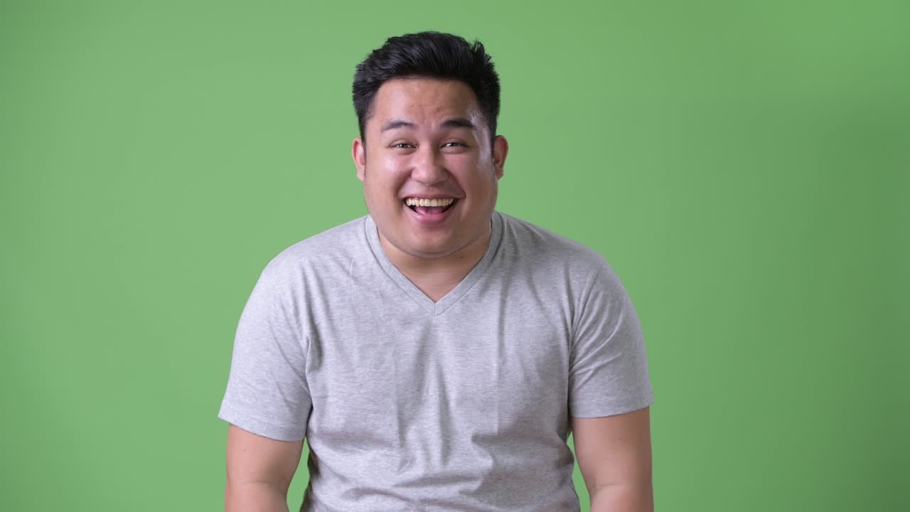 초록색 배경에 젊은 잘생긴 과체중 아시아인