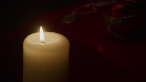 candlelight flickers next to wiccan altar with ritual offering bowl, closeup