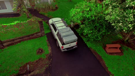 ascending aerial of back house yard, track van located and parked in front of the house, daytime capture, suburban lifestyle concept