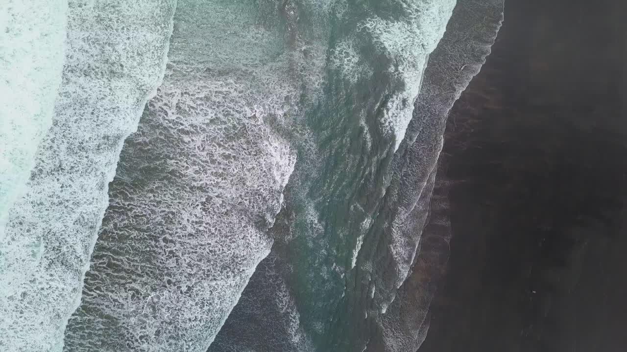 Moody overhead view of the black sand and surf in New Zealand