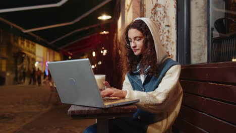 teenage girl study education online distant job with laptop in city street cafe drinking coffee