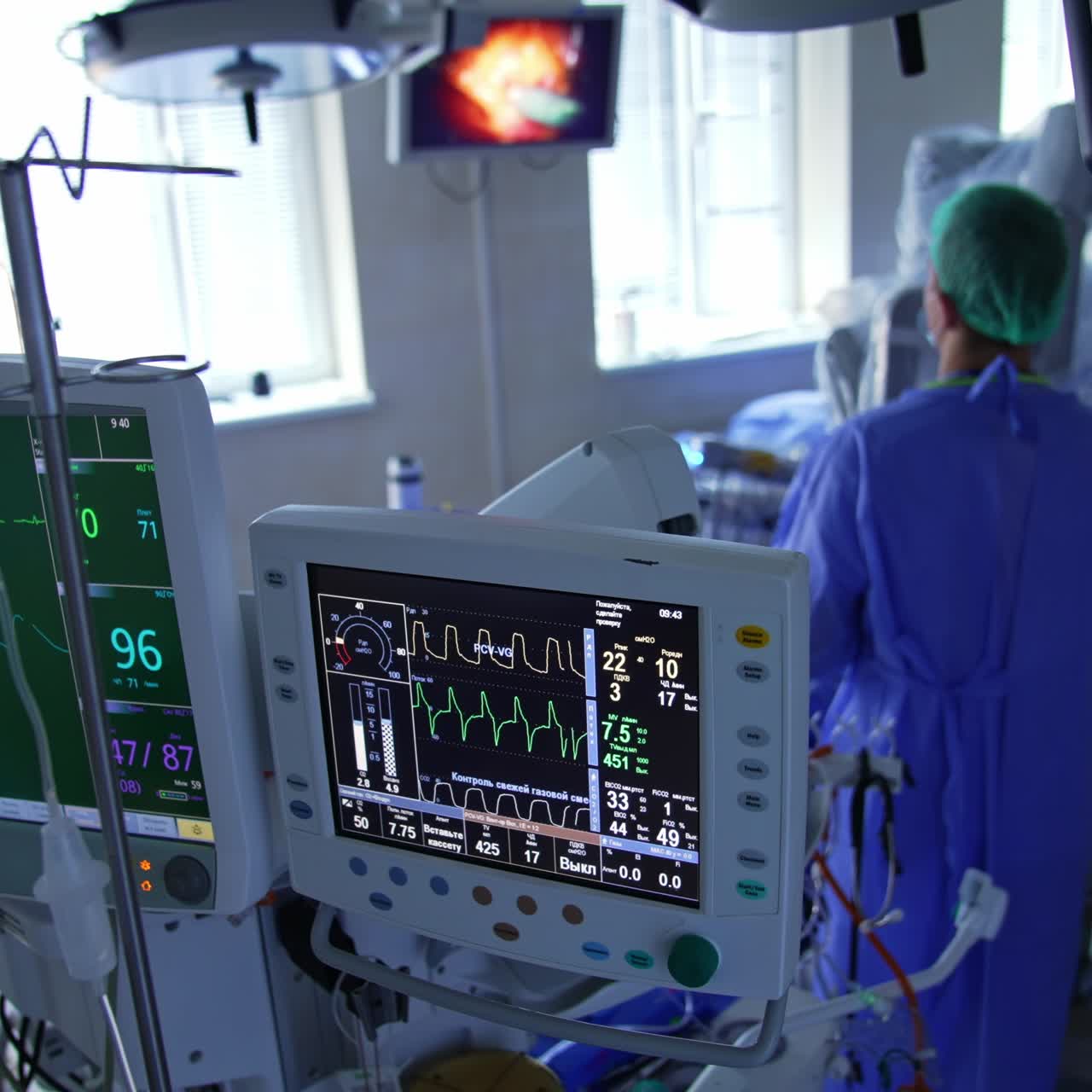 Medical equipment monitors for control of patient's condition at surgery. Doctors perform the procedure looking at the screen on the wall