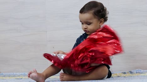 Lindo-Niño-Pequeño-Jugando-Con-Papel-Deformado-De-Color-Rojo-En-El-Interior