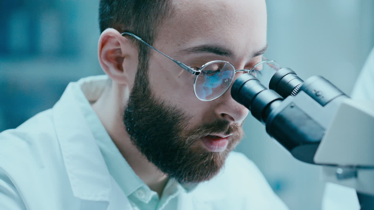 Scienziato che guarda al microscopio e parla con l'assistente in laboratorio