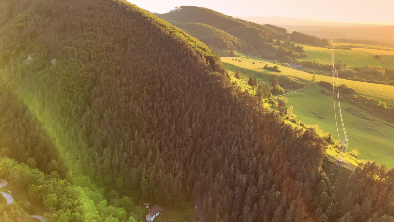 Beautiful sunset over forested hills. Golden sunlight bathes the green hills and dense forest during a peaceful sunset, creating a tranquil atmosphere