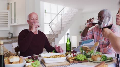 Diverse-senior-couples-sitting-by-a-table-drinking-wine-and-eating-dinner