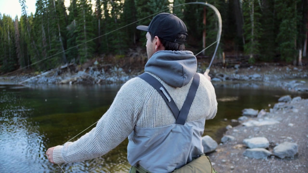 Pengambilan gambar dari darat profil sedang seorang nelayan tunggal sedang memancing di danau alpine yang tenang di Grand Mesa Colorado, memancing ikan trout pelangi dan brook di Pegunungan Rocky