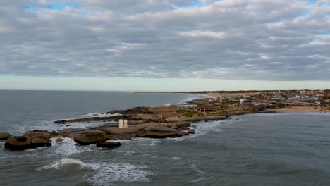 Drone-moving-over-a-clustered-settlement-on-the-ocean-show-of-Punta-del-Diablo