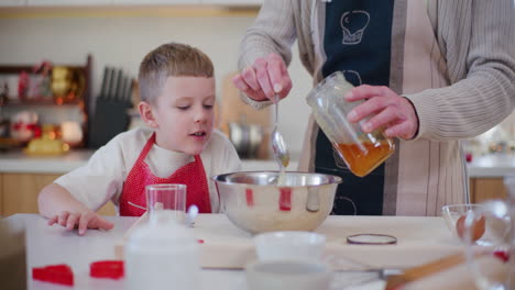 padre e hijo vierte miel en el cuenco mientras hornean pasteles