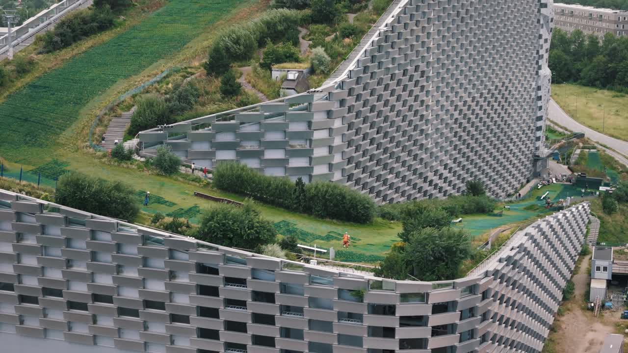 Close tracking of family skiing on Copenhill with view of energy plant architecture, Copenhagen