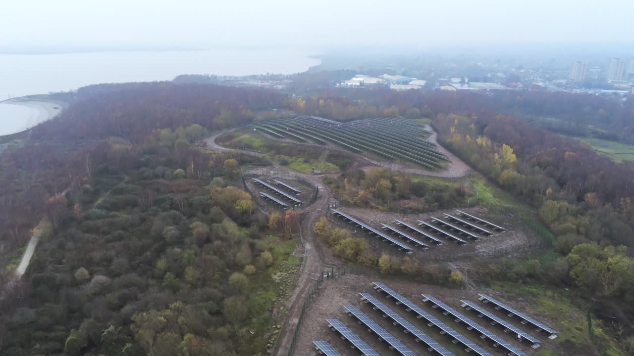 Solar panel array rows aerial view misty autumn woodland countryside high wide orbit shot