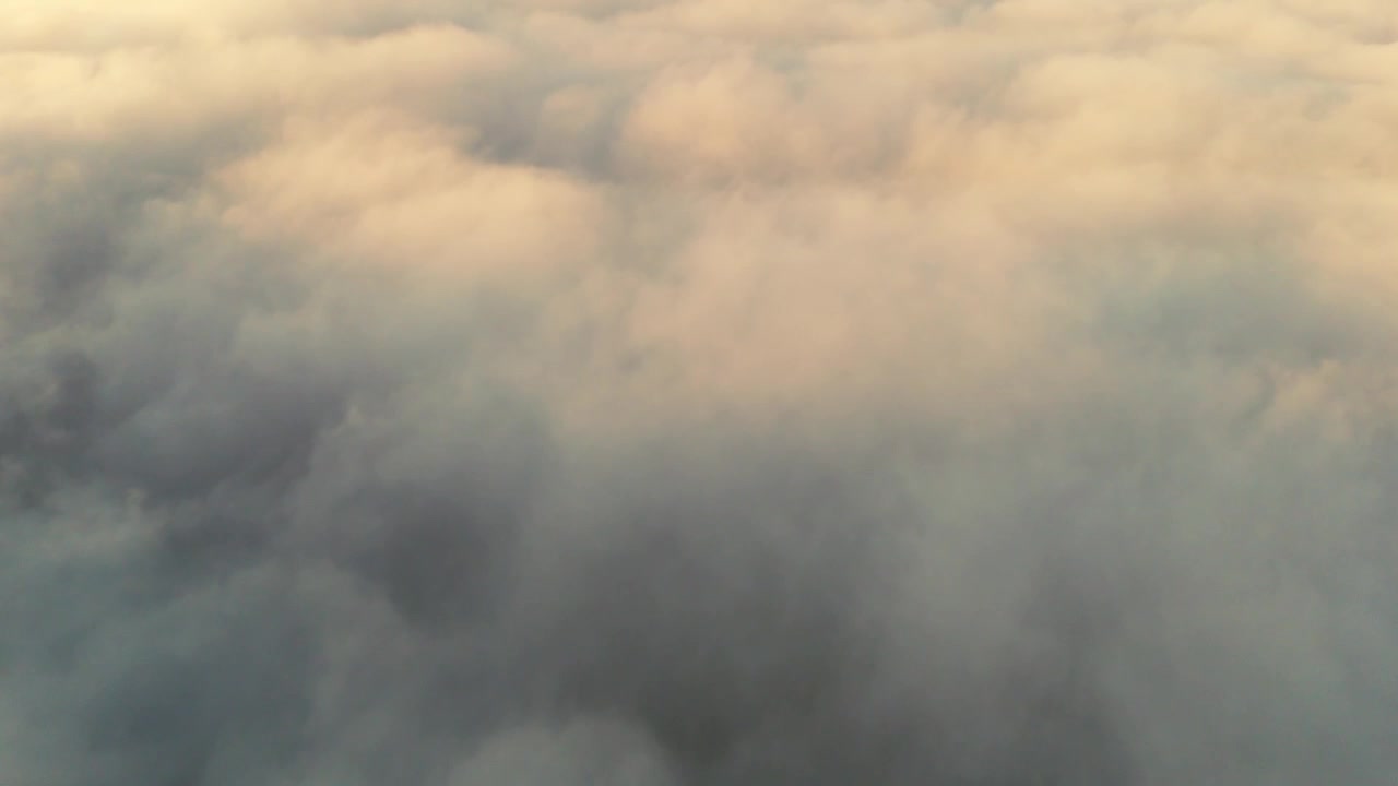 Tranquil aerial view of a soft sea of clouds glowing with warm golden hues during sunrise