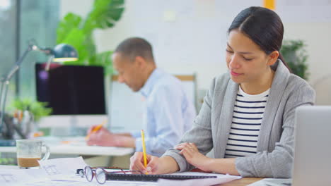 male and female architects working in office at desks on plans for new building