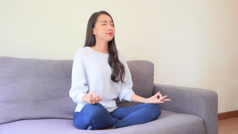 a pretty young woman sits in a yoga pose on the couch