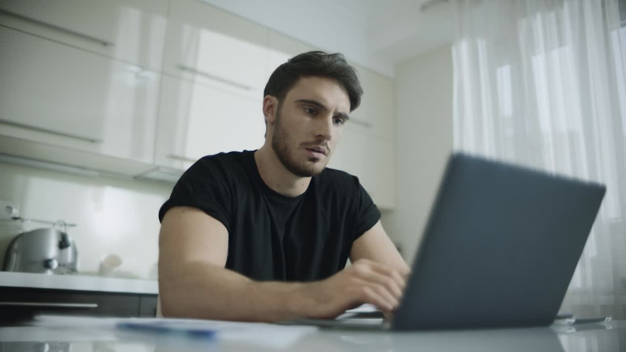 hombre joven escribiendo computadora portátil en casa. hombre de negocios pensativo usando computadora