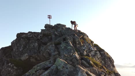 Una-Mujer-Joven-Y-En-Forma-Está-Bajando-Por-Las-Grandes-Rocas-Y-Peñascos-De-La-Cima-De-La-Montaña-Festvågtind-Con-Su-Mochila-Y-Botas-De-Montaña