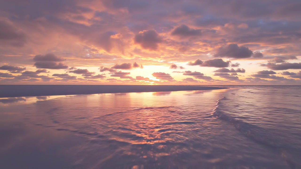 Vibrant sunset clouds reflected in the calm ocean tide