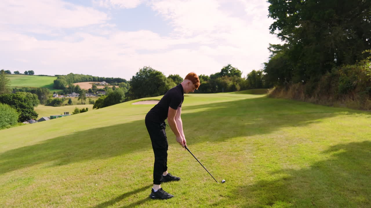 Male golf player playing golf, hitting the ball with club on a golf course on a sunny day