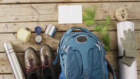equipo de campamento con mochila, botas y espacio de copia sobre fondo de madera.