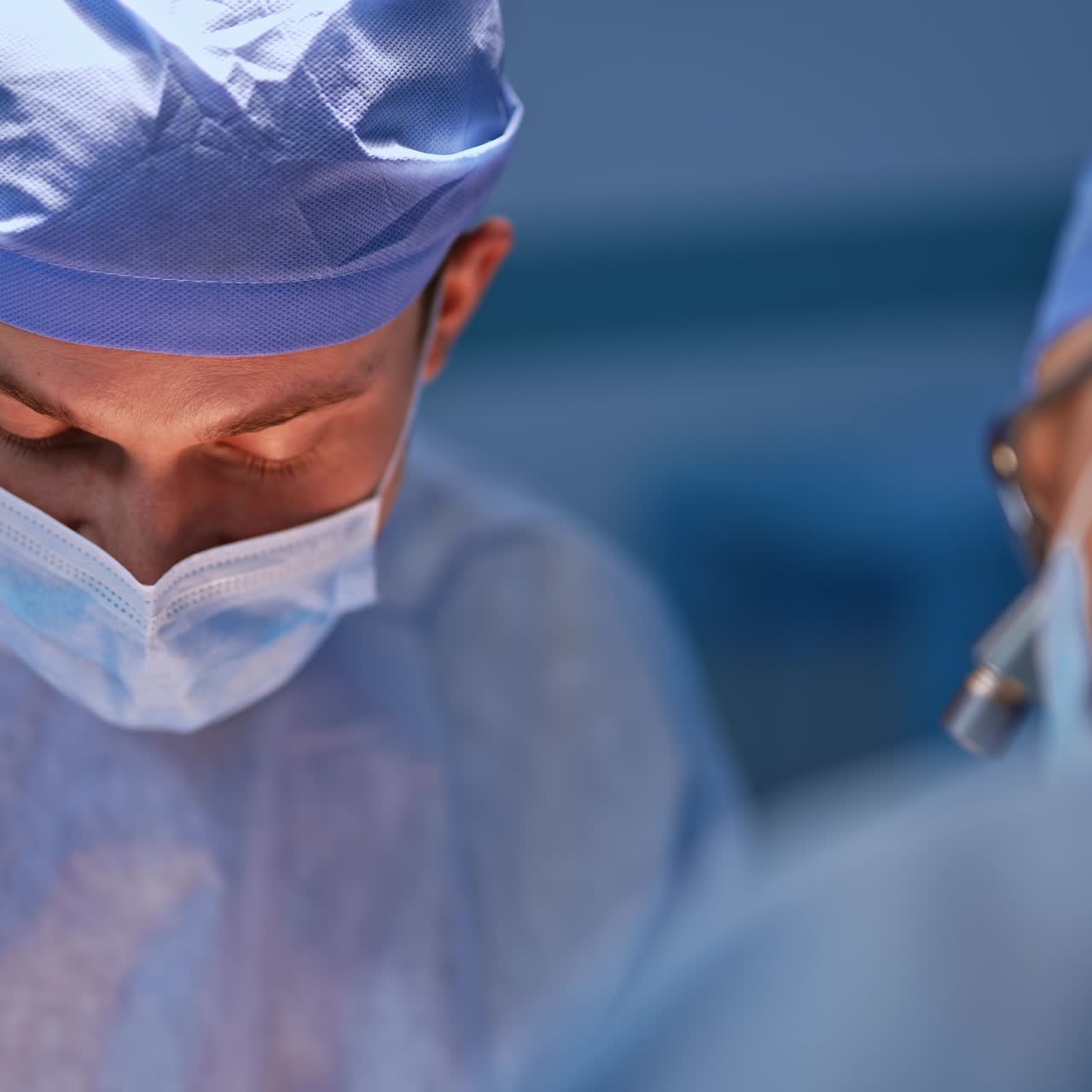 Due dottori in maschera chini sul paziente operato. Chirurghi impegnati durante un'operazione. Primo piano. Sfondo sfocato