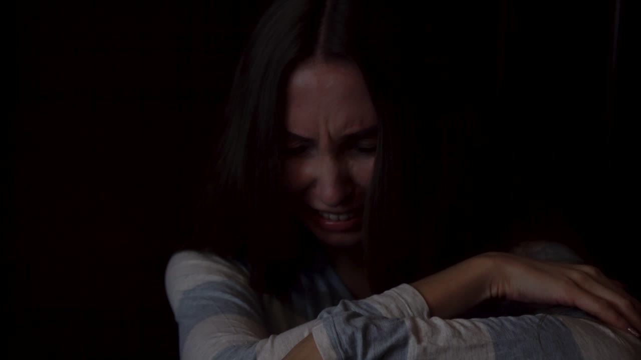 una mujer llorando en la oscuridad.