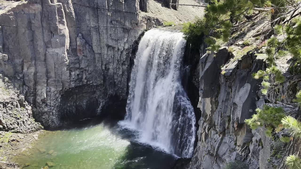 vista de ariel de la cascada que brilla bajo el sol mientras cae sobre impresionantes formaciones rocosas