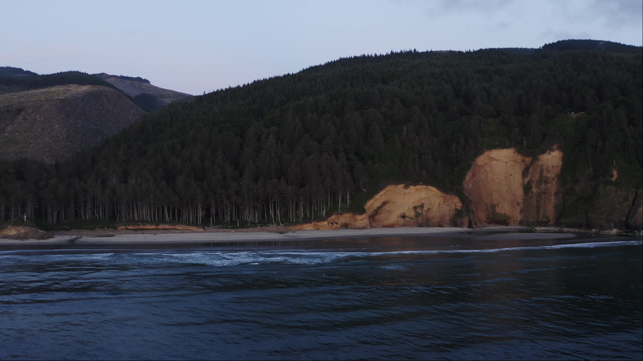 colina boscosa, playa, en la costa de oregón, vista estática desde el agua, olas en cámara lenta