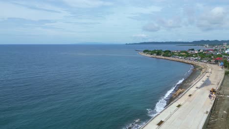 Aerial,-Rising,-Drone-Shot-of-Beautiful-Bay-and-Seawall-facing-Coastal-Village-in-Virac,-Catanduanes,-Philippines,-Asia