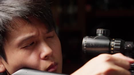 asian man sniper adjusting and looking through scope of rifle then shoot, close up