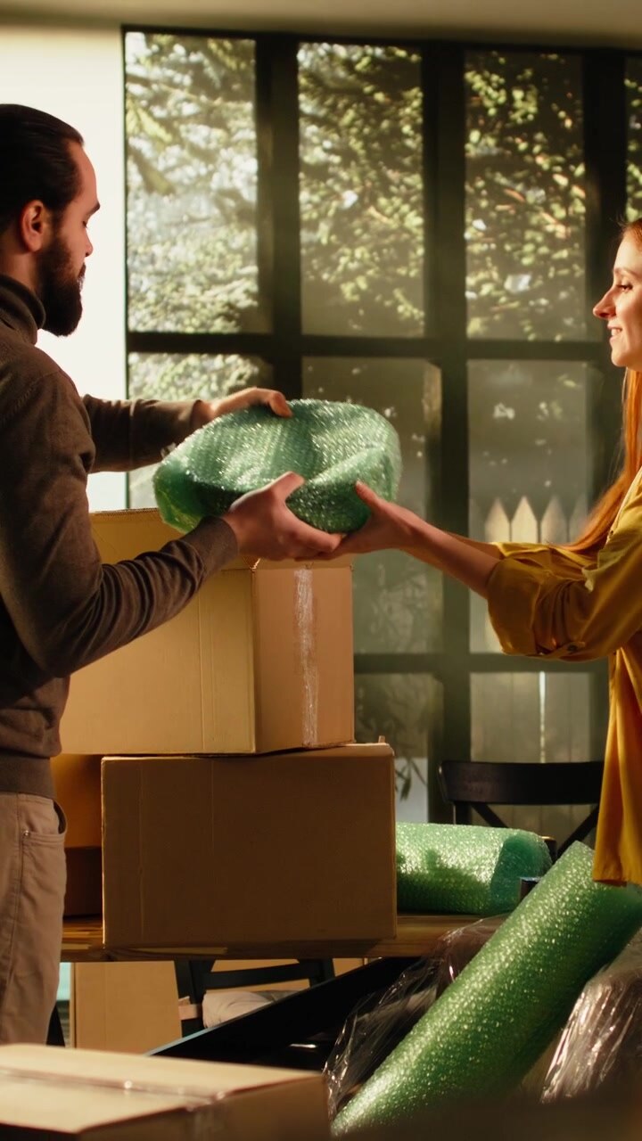 Vertical Video Wrapped furniture, unpacking household items, man and woman, relocation day
